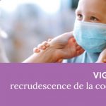 Enfant portant un masque chirurgical et regardant un adulte qui lui ajuste le masque.